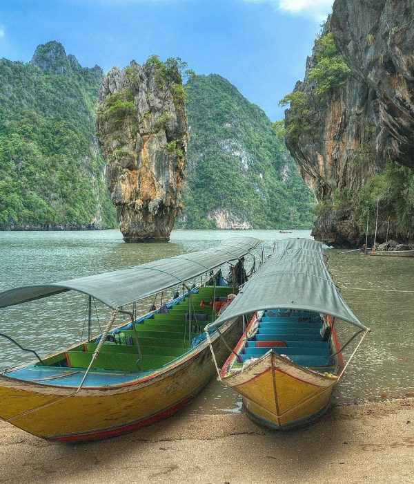 Spiaggia Thailandese immersa nella natura con barche tipiche del posto