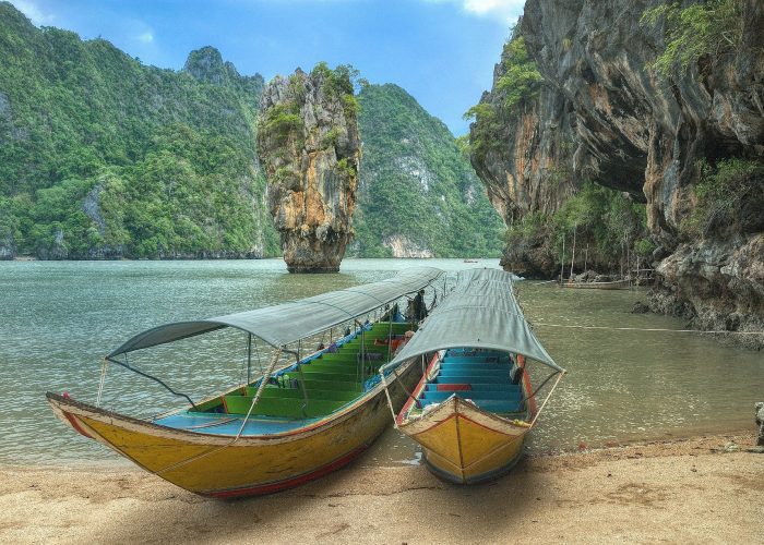 Spiaggia Thailandese immersa nella natura con barche tipiche del posto
