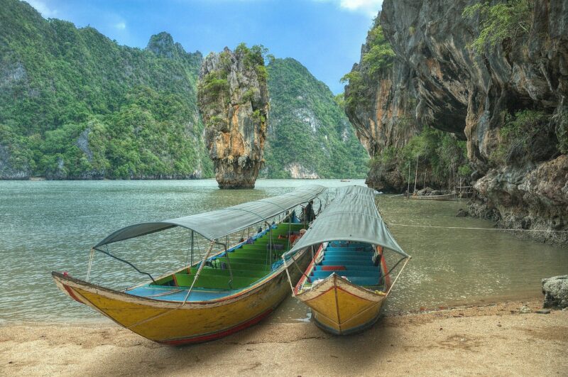 Spiaggia Thailandese immersa nella natura con barche tipiche del posto