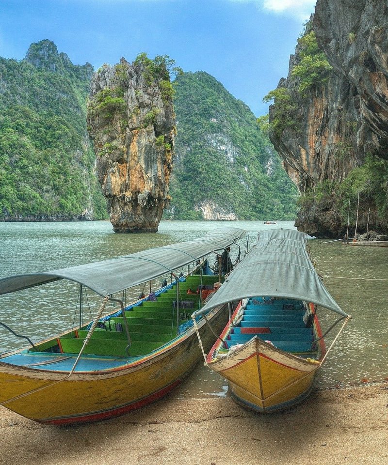 Spiaggia Thailandese immersa nella natura con barche tipiche del posto