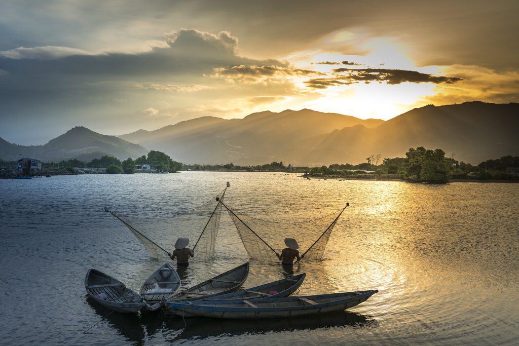 Paesaggio Thailandese durante il tramonto di due pescatori locali
